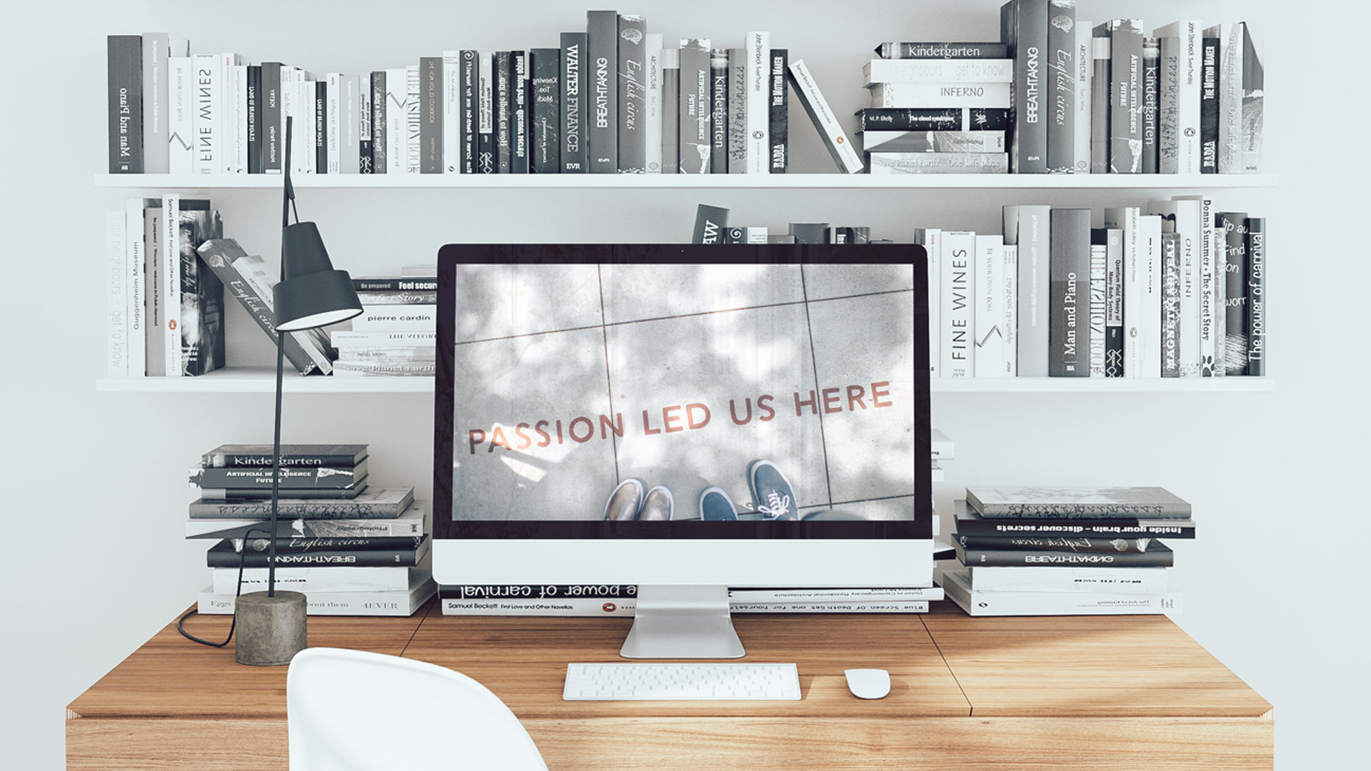 Schreibtisch im Studio mit Büchern und „Passion led us here"-Bild auf dem Display